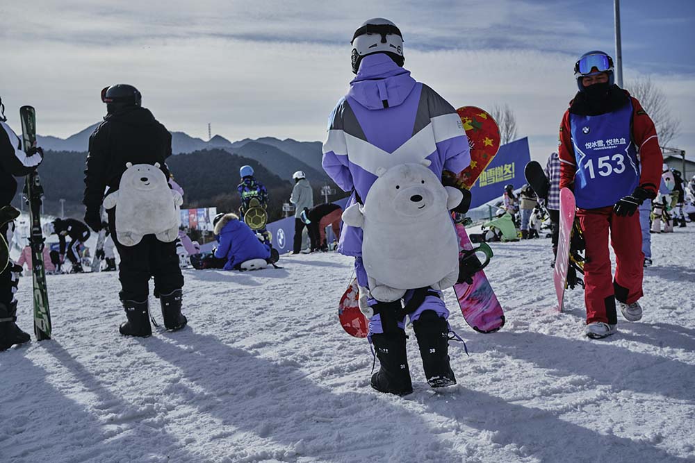 Skiers carry snowboards and skiing gear to a slope at Nanshan Ski Resort, Beijing, Jan. 8, 2022. Wu Huiyuan/Sixth Tone