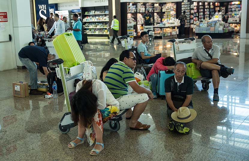 Tourists wait for flight information following delays at Ngurah Rai International Airport in Denpasar, Bali, Indonesia, July 13, 2015. Agung Parameswara/Getty Images/VCG