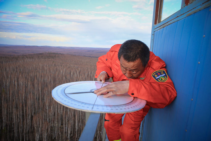 Cao Zhiguo demonstrates how to use a compass to locate a fire from his watchtower in the Greater Hinggan Mountains, Mohe County, Heilongjiang province, April 21, 2017. Zhang Yanliang/Sixth Tone