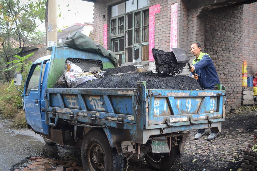 Su Jianhong shovels coal from his yard into a three-wheeled truck in Taiyuan, Shanxi province, Oct. 18, 2017.  Fan Liya/Sixth Tone
