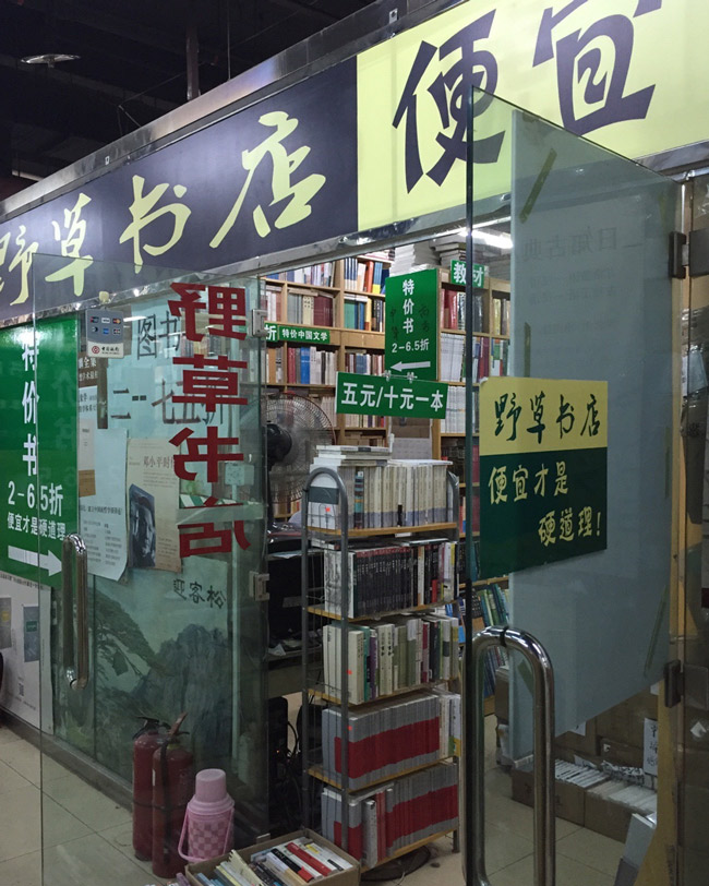 An exterior view of the now closed Peking University campus location of the Wild Grass Bookstore in Beijing, 2015. A sign reading “price has the final say” can be seen on its front door. From @芳美明子 on Weibo