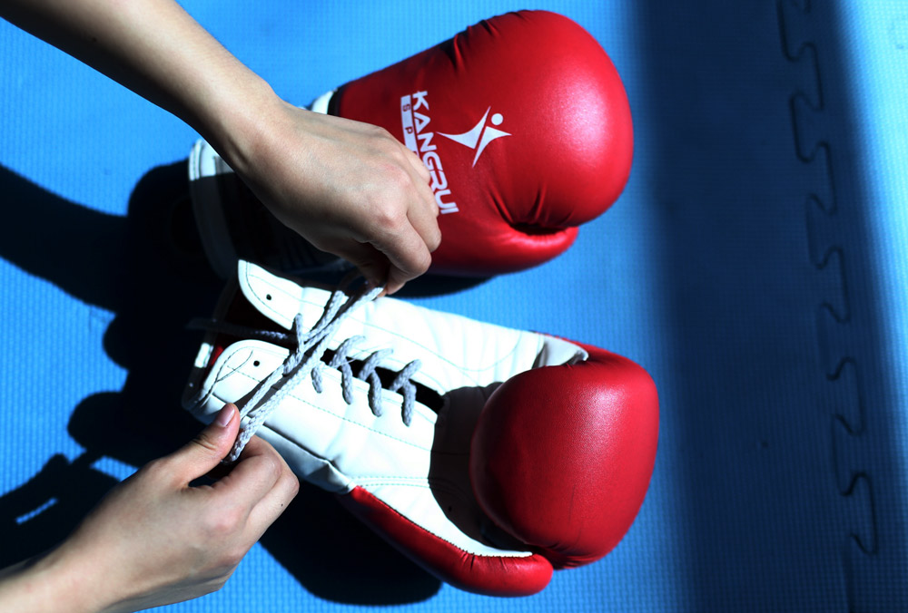 A woman laces up a pair of boxing gloves in Haikou, Hainan province, 2015. VCG