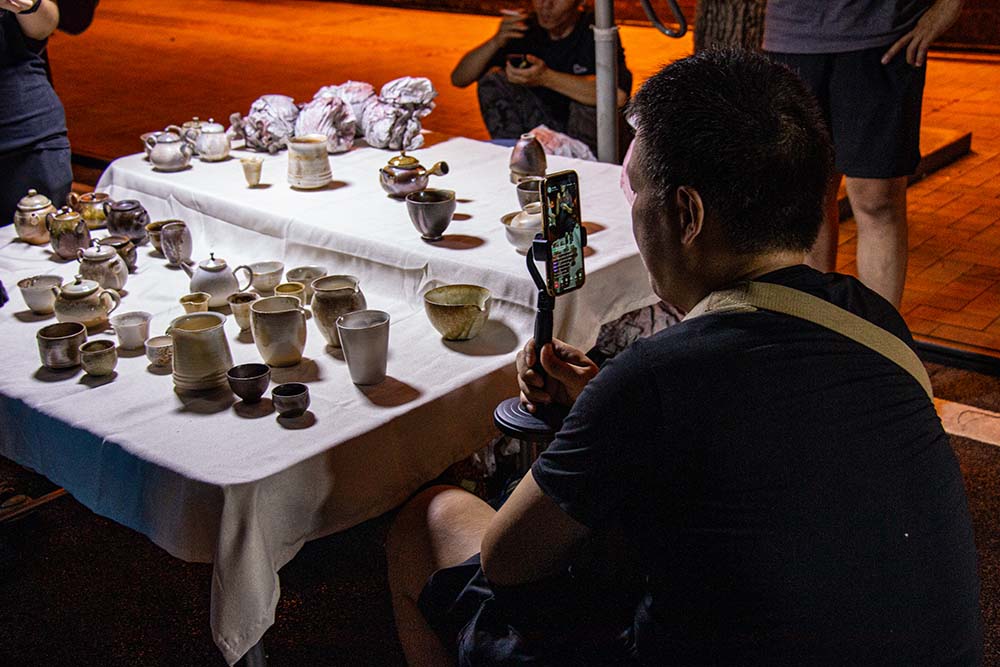 A man hosts a livestream at an outside stall selling pottery in Jingdezhen, Jiangxi province, July 2021. Huang Sha and Li Jinrui for Sixth Tone