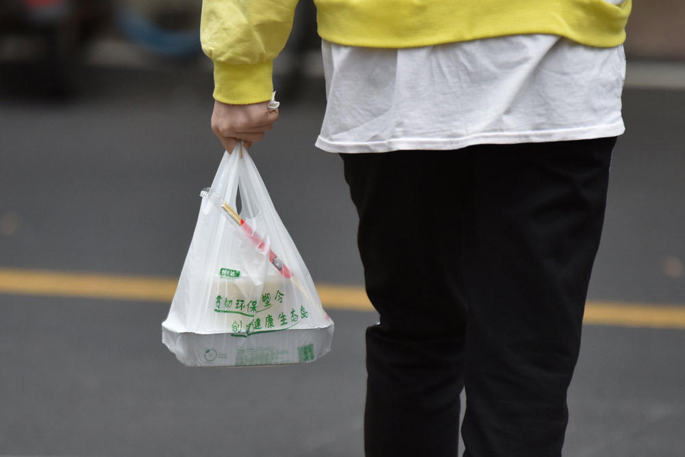 A college student holds a biodegradable plastic takeaway bag in Haikou, Hainan province, Nov. 30, 2020. Lu Junmin/VCG