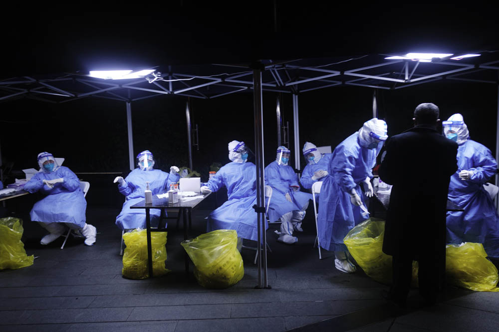 Medical workers rest in the early hours of the morning after an extended shift conducting COVID-19 tests in Xuhui District, Shanghai, March 10, 2022. Wu Huiyuan/Sixth Tone
