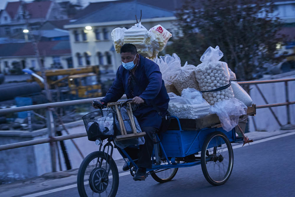 A snack vendor carries his goods home in Gucun Town, Baoshan District, Shanghai, March 16, 2022. Wu Huiyuan/Sixth Tone