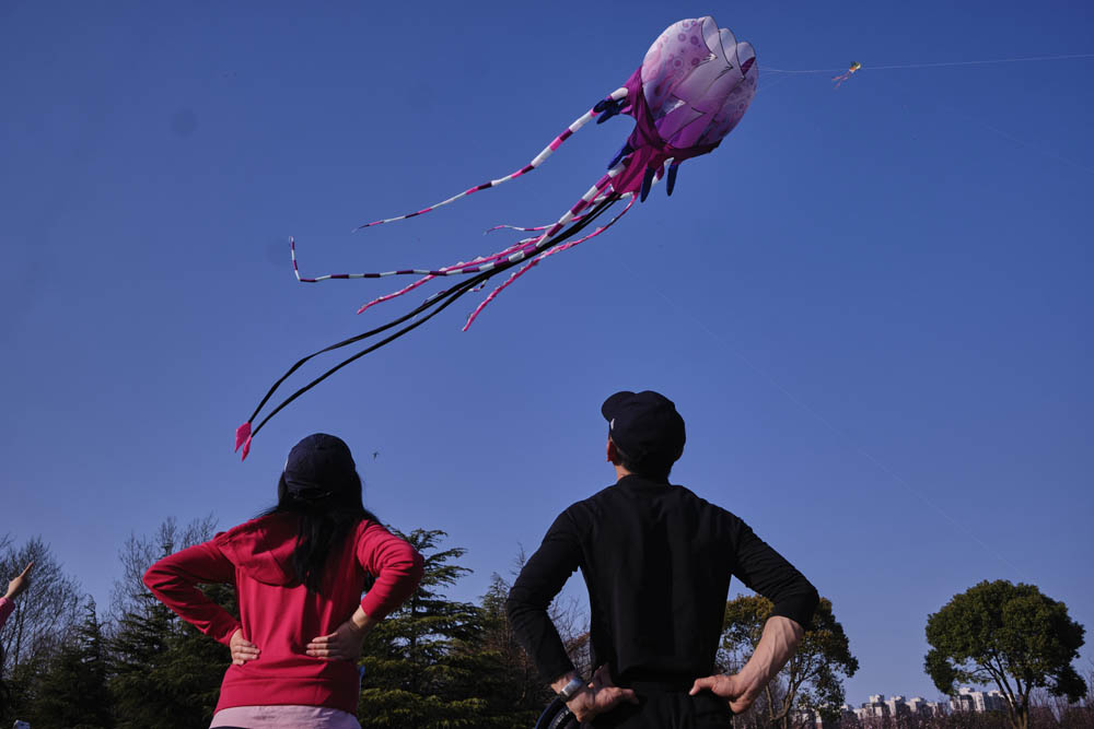 A couple watches a kite fly past them at Gucun Park, Shanghai, March 13, 2022. Wu Huiyuan/Sixth Tone