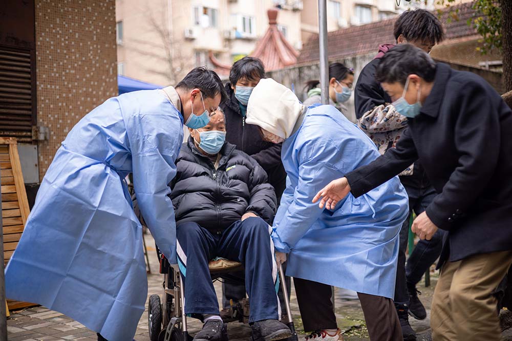 Volunteers help an older man with his COVID-19 test in Shanghai, March 18, 2022. VCG