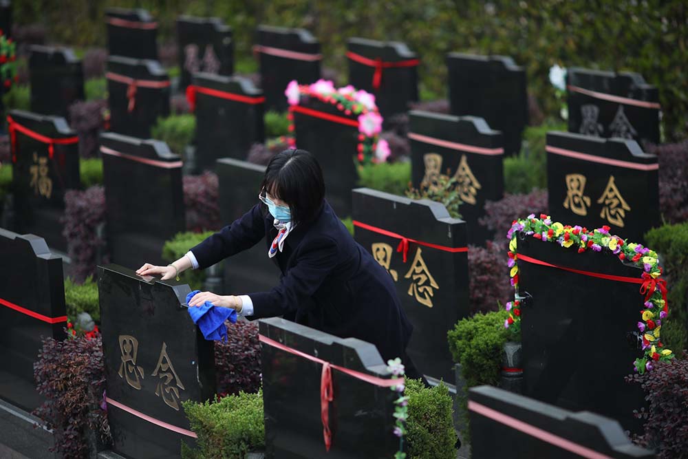 A woman at a public cemetery sweeps gravesites for people could not come themselves due to COVID-19, in Nanjing, Jiangsu province, March 19, 2022. IC
