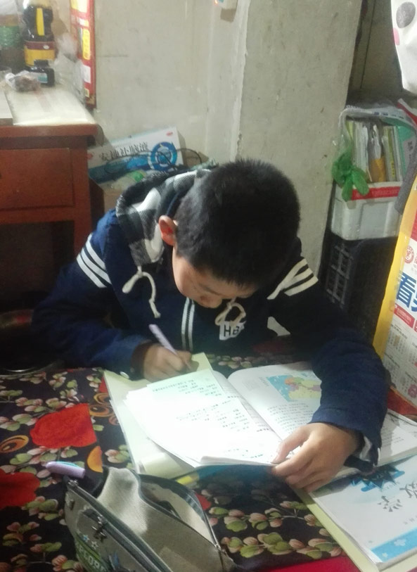 A boy does homework in a home rented by his mother, 2017. Courtesy of Qi Weiwei