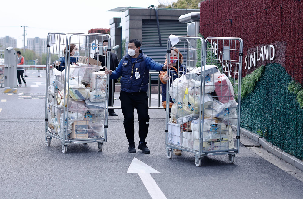 Staff members from a food company deliver packages ordered through a “group-buying” scheme to a residential community in Shanghai, April 1, 2022. Yin Liqin/CNS/VCG