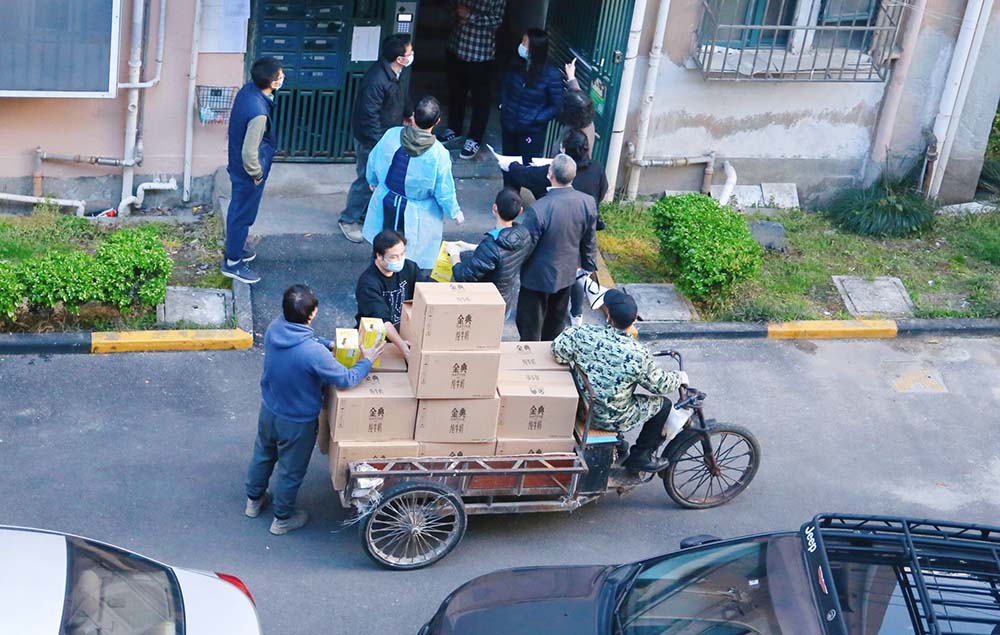Grassroots workers and volunteers deliver groceries at a compound in Shanghai, March 26, 2022. IC