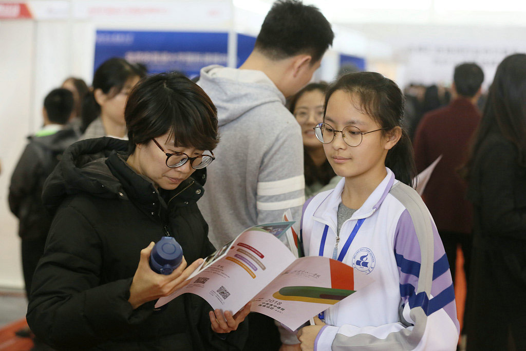 A mother readings marketing materials of an international school in Beijing, 2018. VCG