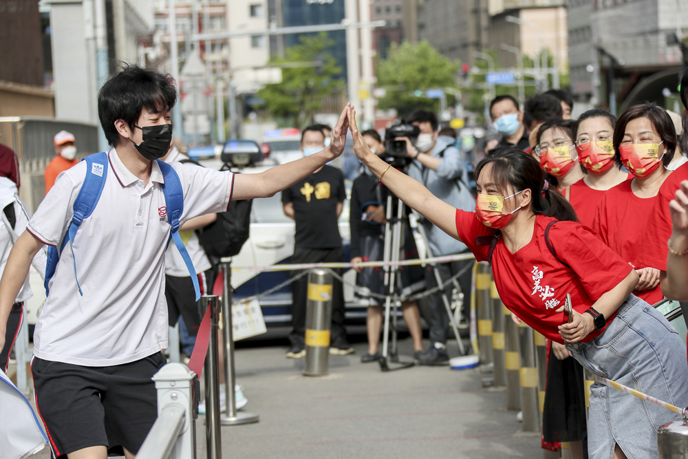 A student high-fives his teacher before entering school for the national college entrance exam in Beijing, June 7, 2022. VCG