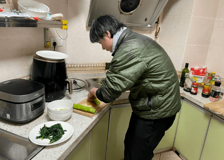 Jiang Xueqin cooks lunch at home in Chengdu, Sichuan province, 2022. Wei Xiaohan/White Night Workshop