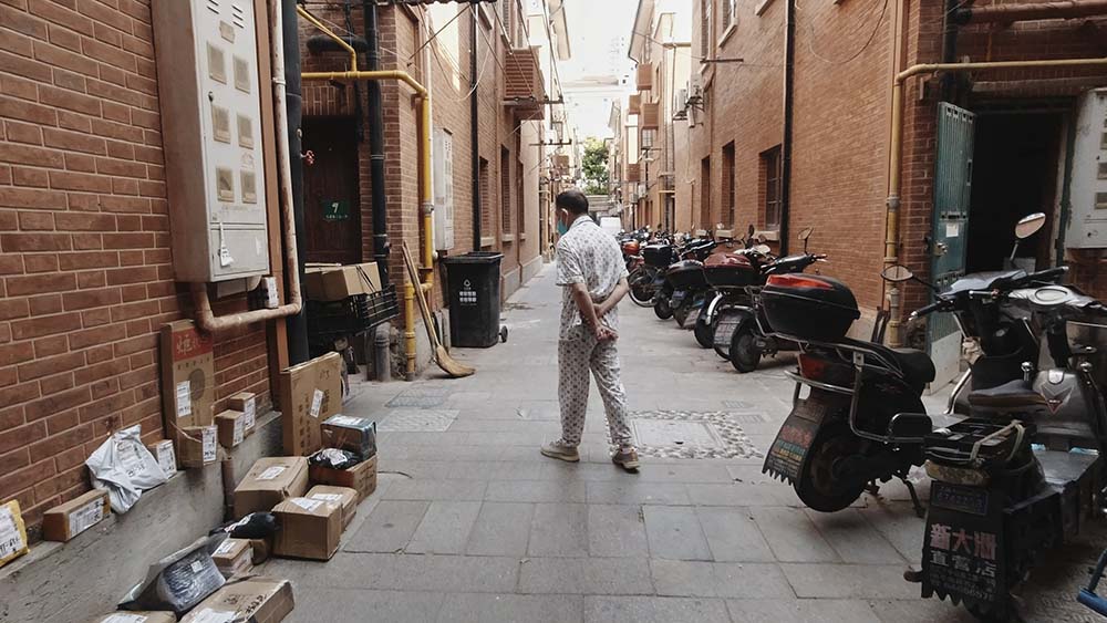 A man walks through the lanes inside Shenchengli, Shanghai, June 27, 2022. Wu Huiyuan/Sixth Tone