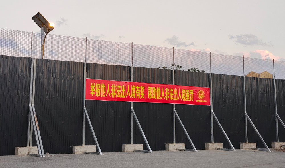 A banner posted on the China-Myanmar border wall in Ruili, Yunnan province, February 2022. The banner promises rewards for those who turn in undocumented immigrants and punishments for anyone who helps them. Courtesy of the author