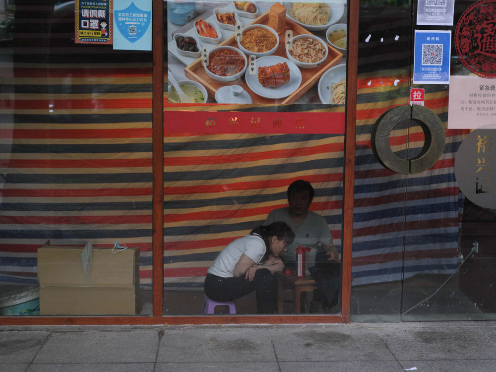 Two people live inside a restaurant during the lockdown in Shanghai, May 29, 2022. Zhou Pinglang for Sixth Tone