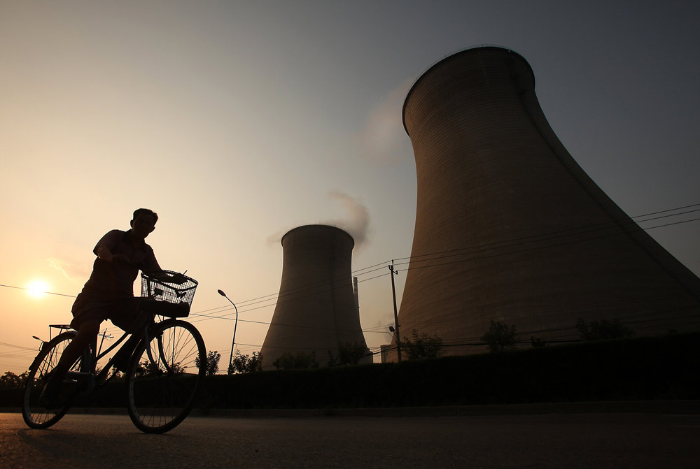 A cyclist rides by a coal-powered energy plant in Beijing, July 21, 2010. Stephen Shaver/UIP via VCG
