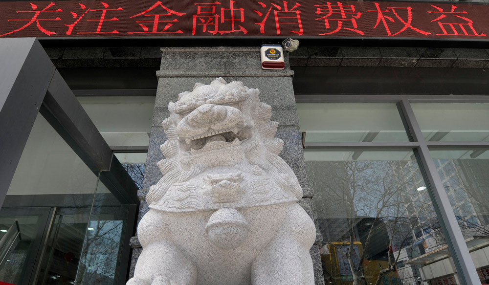 A stone lion in front of a bank in Nanjing, Jiangsu province. The banner says “focus on the rights of financial consumption.” VCG