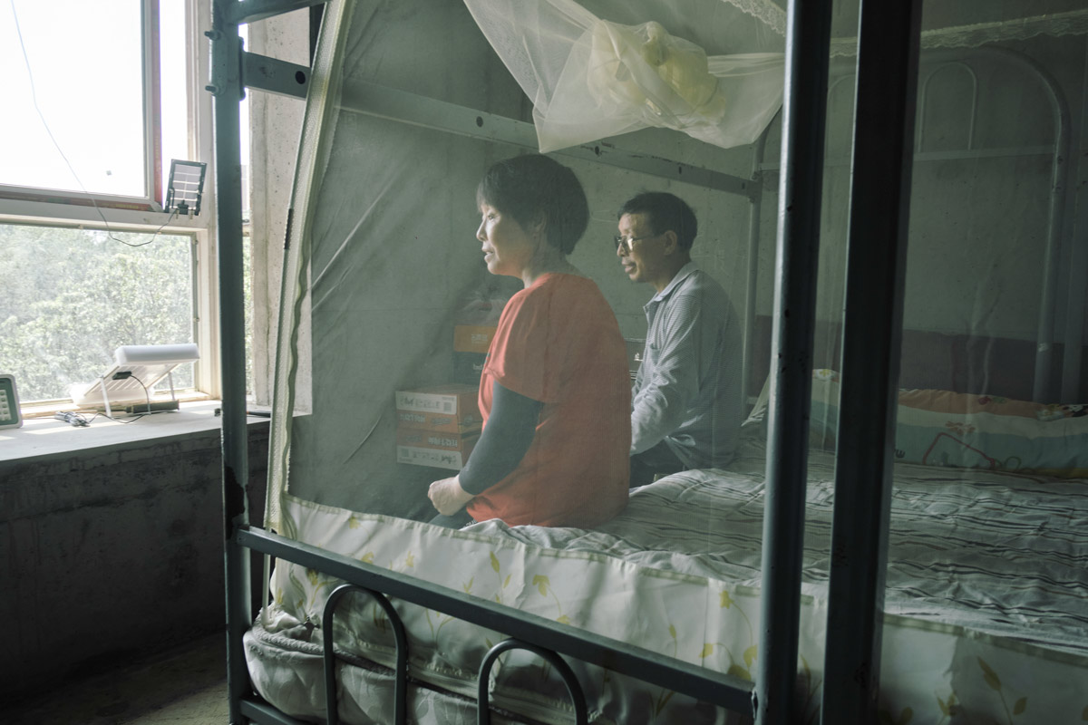 Zhou Zongzhen (left) and Wang Xudong (right) sit in their bedroom inside an unfinished building, in Xi’an, Shaanxi province, August 2022. Wu Huiyuan/Sixth Tone
