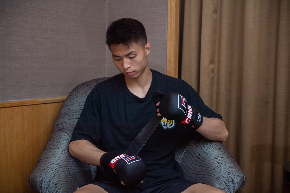 Xie Bin puts on his boxing gloves, in Singapore, June 2022. David Ash for Sixth Tone