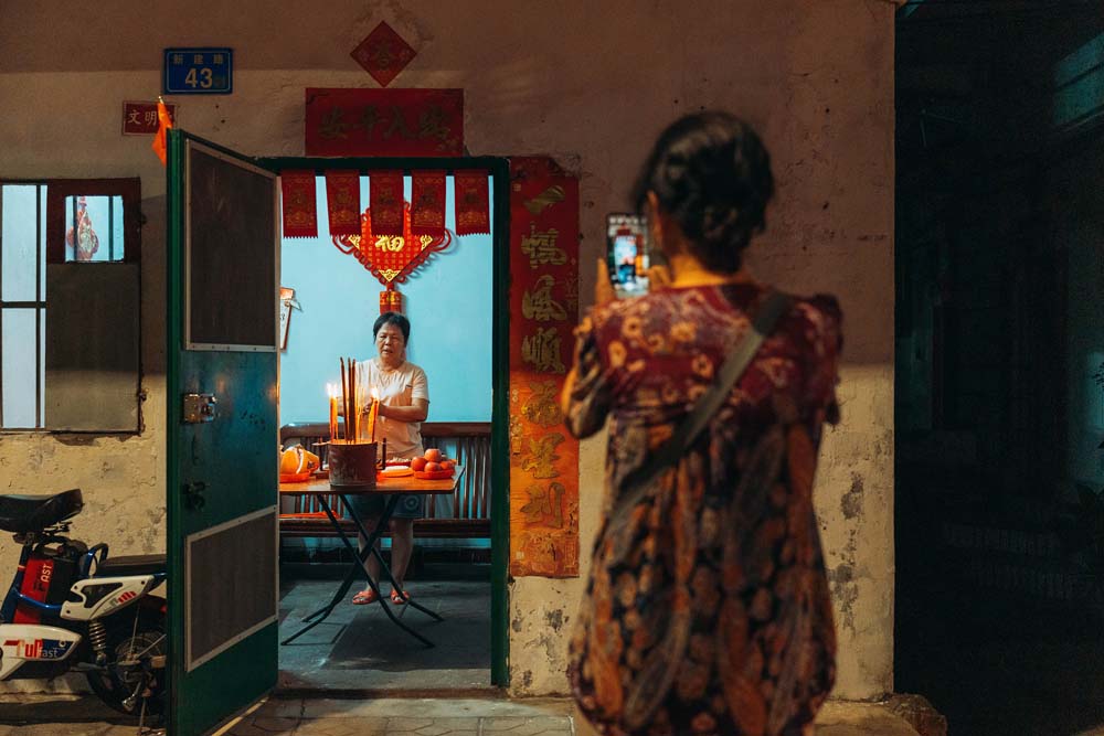 A woman takes photos of a worship scene on the day of Mid-Autumn Festival at a village in Huizhou, Guangdong province, Sept. 10, 2022. In Huizhou, people usually worship their ancestors and the moon during the Mid-Autumn Festival. VCG