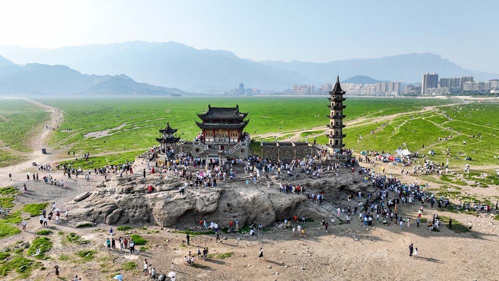 Tourists visit an island temple standing on the dried-up bed of Poyang Lake in Jiujiang, Jiangxi province, Sept. 10, 2022. VCG