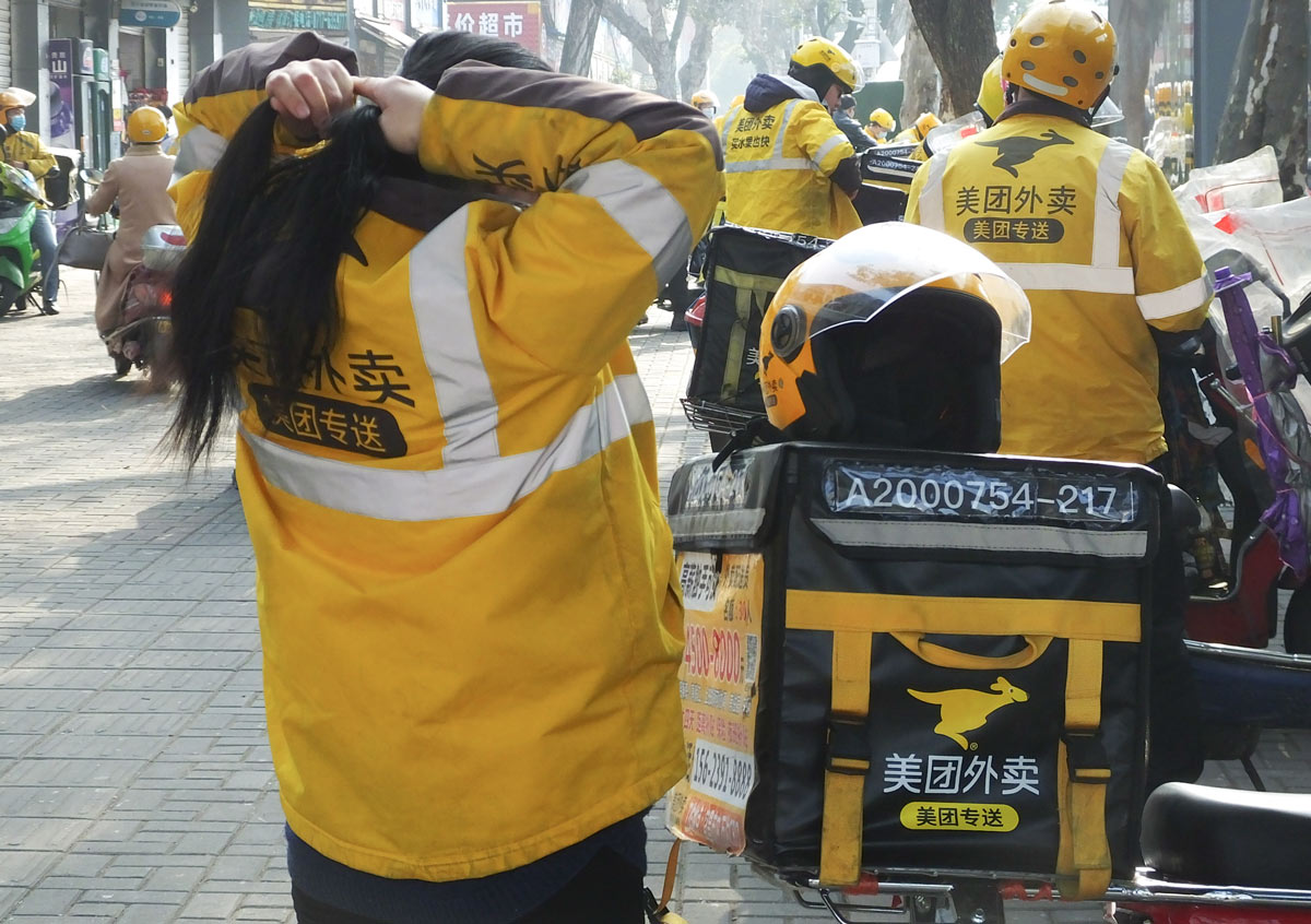 A delivery rider ties up her hair in Yichang, Hubei province, 2021. Liu Junfeng/VCG