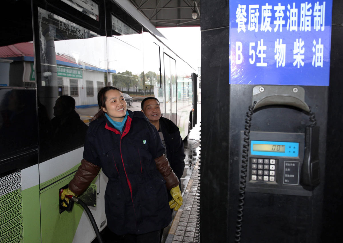 A woman fills a bus with fuel comprised of 5% used cooking oil in Shanghai, 2015.  Pei Xin/Alamy