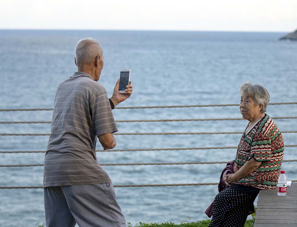 A man takes photos for a woman at a beach in Wanning, Hainan province, July 15, 2022. VCG