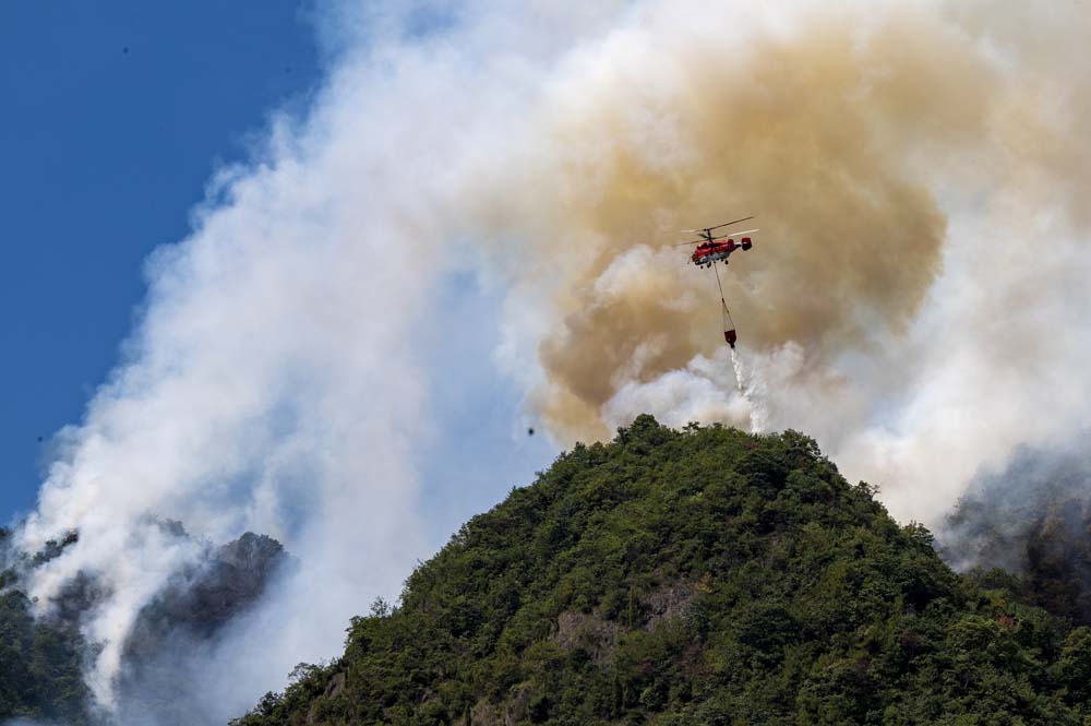 A helicopter tries to put out a mountain fire in Jinhua, Zhejiang province, Oct. 2, 2022. VCG