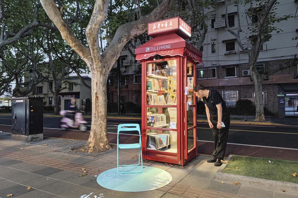 A man looks at a mini bookstore converted from a phone booth in Shanghai, Oct. 2, 2022. VCG