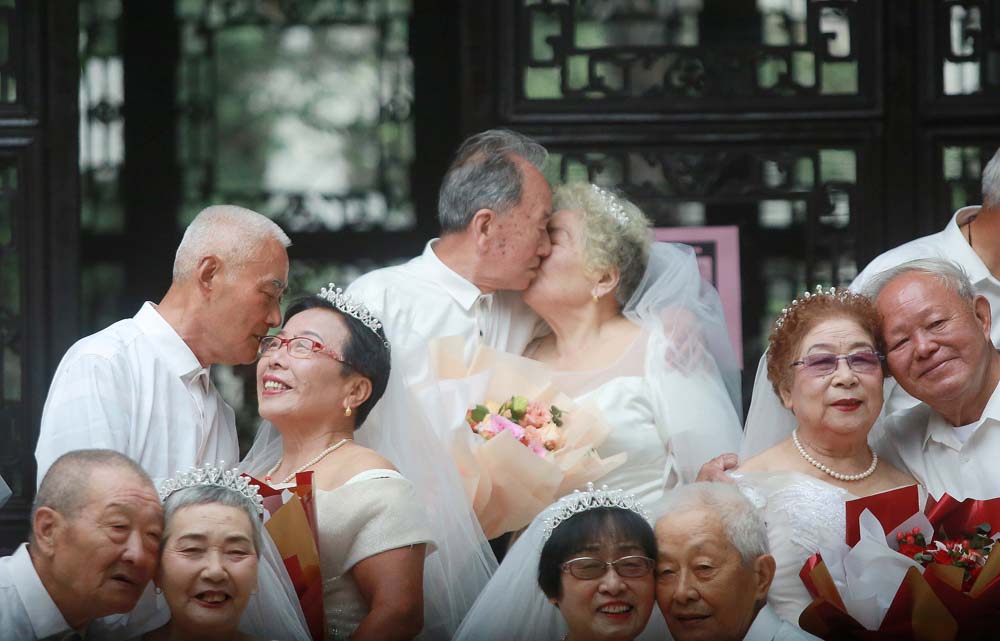 Couples take wedding photos to celebrate their golden wedding anniversaries in Yangzhou, Jiangsu province, Oct. 4, 2022. VCG