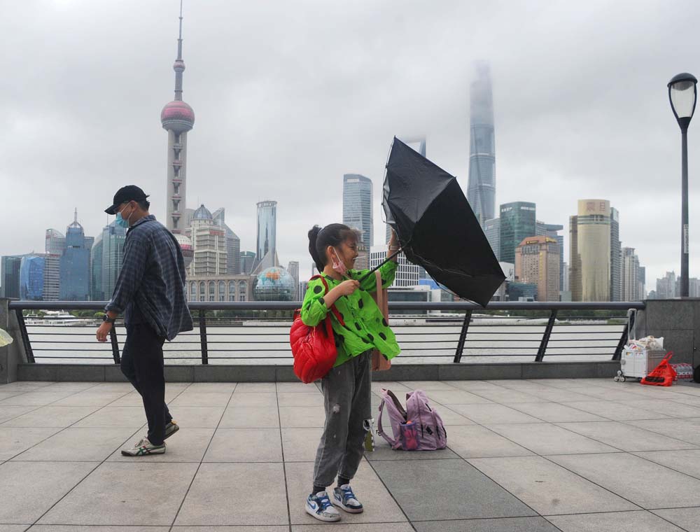 A girl’s umbrella is blown inside-out by heavy wind, in Shanghai, Oct. 4, 2022. Many cities along China’s eastern coastline have experienced temperature drops of more than 10 degrees Celsius this week. VCG
