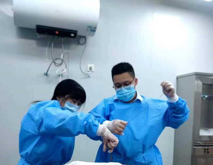 Cha Quanling (right) stitches the wound of a dead body with the help of her colleague in Xiangyang, Hubei province, July 2022. Courtesy of Cha Quanling