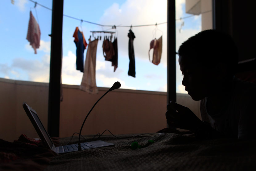 A boy plays on a computer in his family’s rental apartment in Shanghai, July 31, 2012. Wang Juliang for Sixth Tone