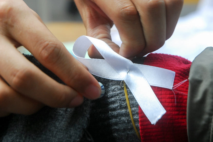 A volunteer attaches a white ribbon, a symbol of anti-domestic violence efforts, to a man’s wrist in Haikou, Hainan province, Nov. 25, 2008. Peng Tong/IC