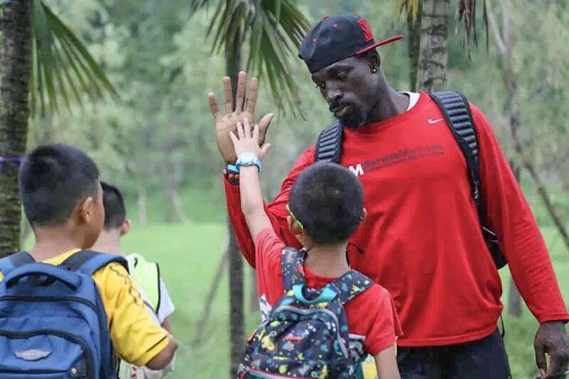Wendell Brown high-fives a young student during a football camp in Chongqing. Courtesy of Emma Liu