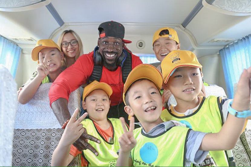 Wendell Brown poses for a photo on a bus with a group of boys participating in a football camp in Chongqing. Courtesy of Emma Liu