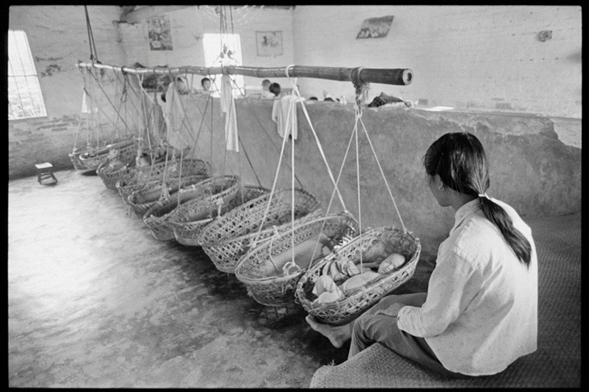 A maid looks after toddlers sleeping in hanging baskets at a nursery set up to take care of farmers’ children in a village in Guangdong province, 1988. Courtesy of Andrew Wong
