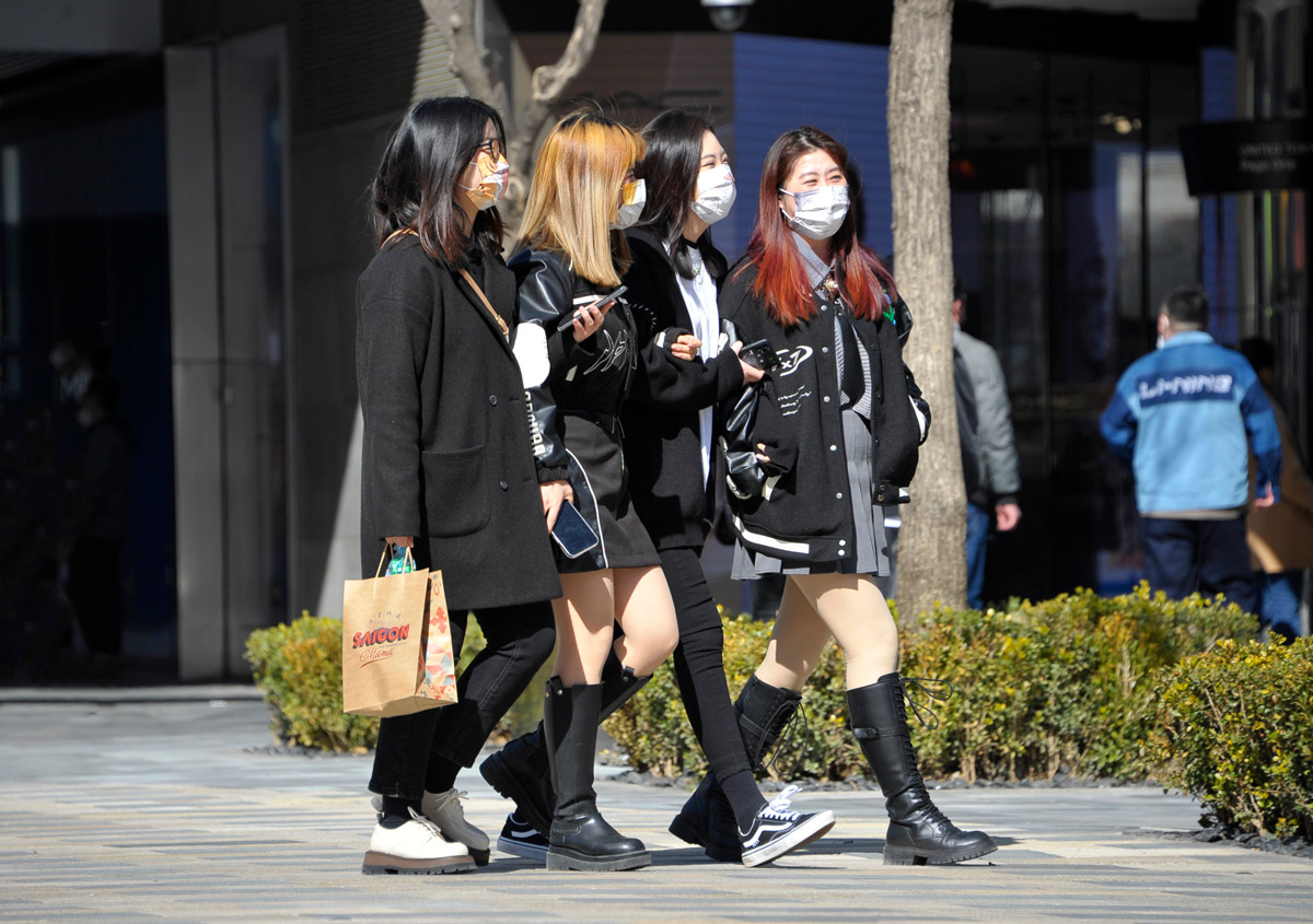 Young women walk on a street in Beijing, March 2022. VCG