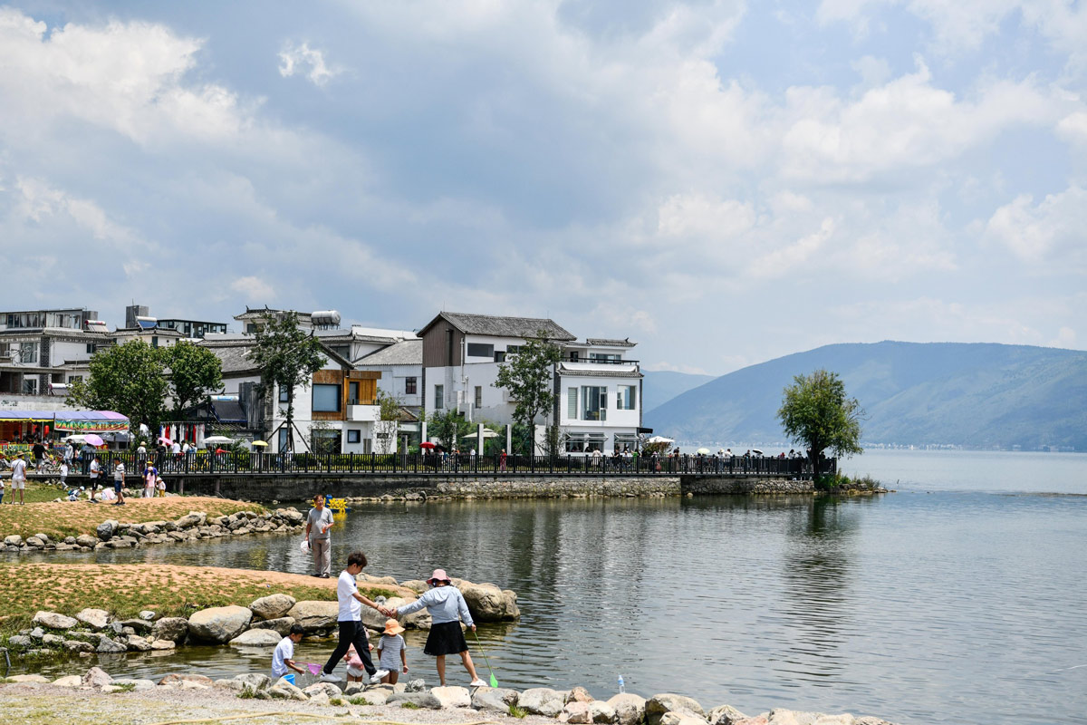 Tourists relax on the shore of Erhai Lake in Dali, Yunnan province, Aug. 11, 2022. VCG