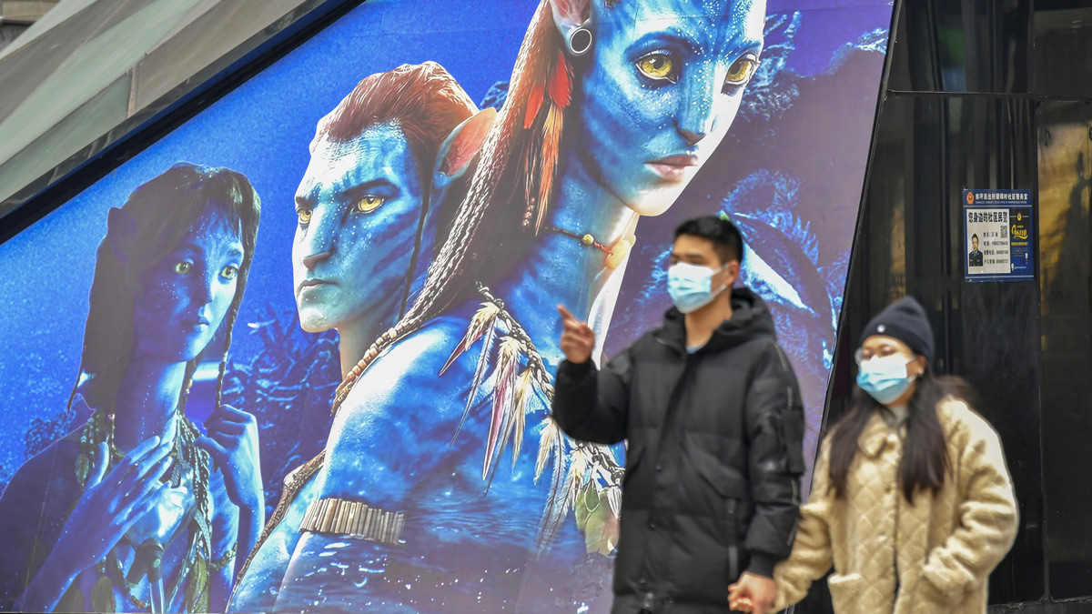 A couple walks past a poster for “Avatar: The Way of Water” in Chongqing, Dec. 20, 2022. IC