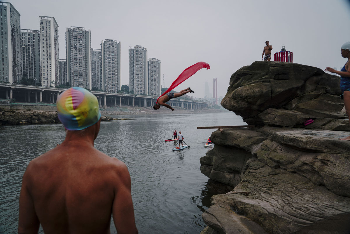 A man jumps headfirst into the Jialing River in Chongqing, June 11, 2022. The area is popular among local divers. VCG