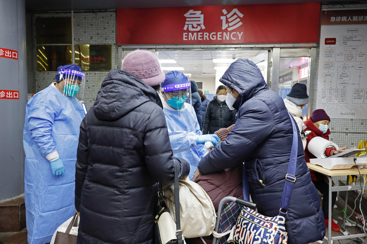 Medical workers check the body temperaturen of a patient outside an emergency room in Shanghai, Dec. 26, 2023. Yin Liqin/CNS/IC