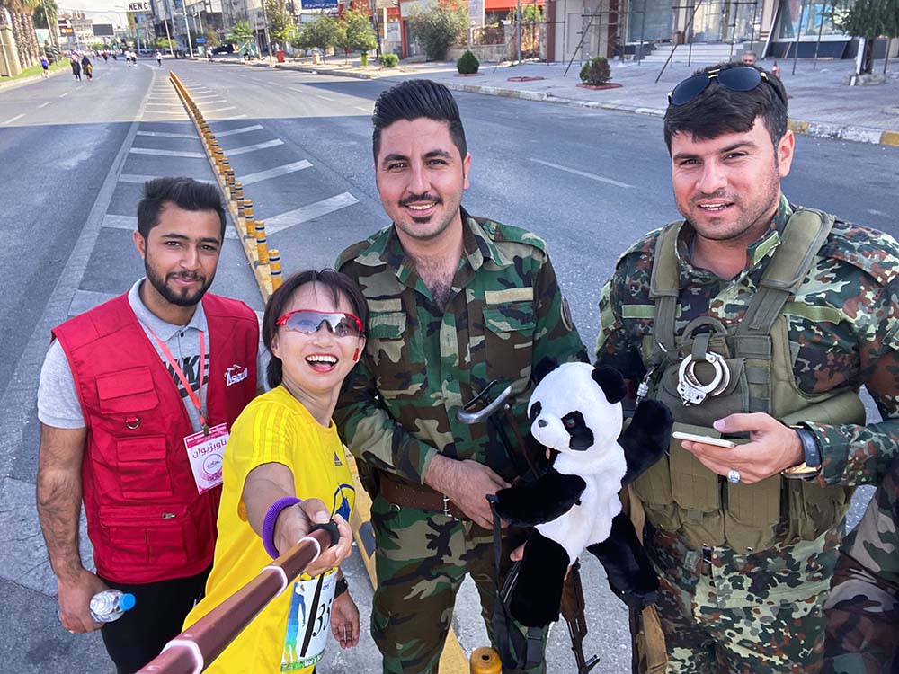 He Yaqing, co-founder of ZX Tour, takes a photo with some soldiers during the Erbil Marathon, which is highly popular among Chinese runners, in Iraq, 2019. Courtesy of ZX Tour