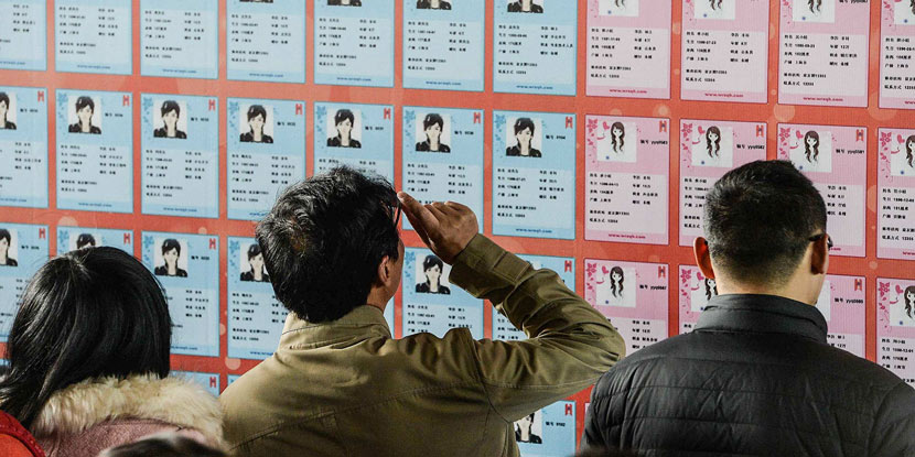 Young singles read fliers bearing the personal information of potential romantic matches, Shanghai, Dec. 20, 2014. Lai Ruining/VCG