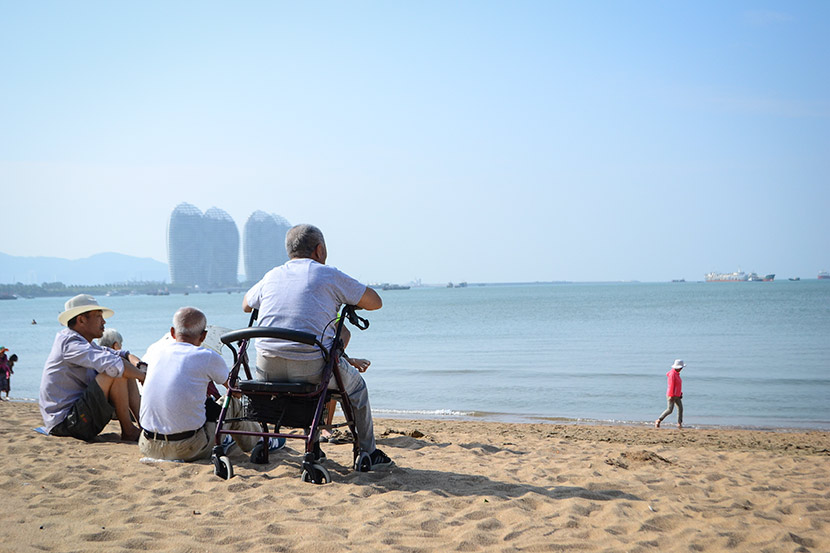 Elderly people enjoy the sunshine on the beach in Sanya, Hainan province, Dec. 8, 2017. Fan Liya/Sixth Tone
