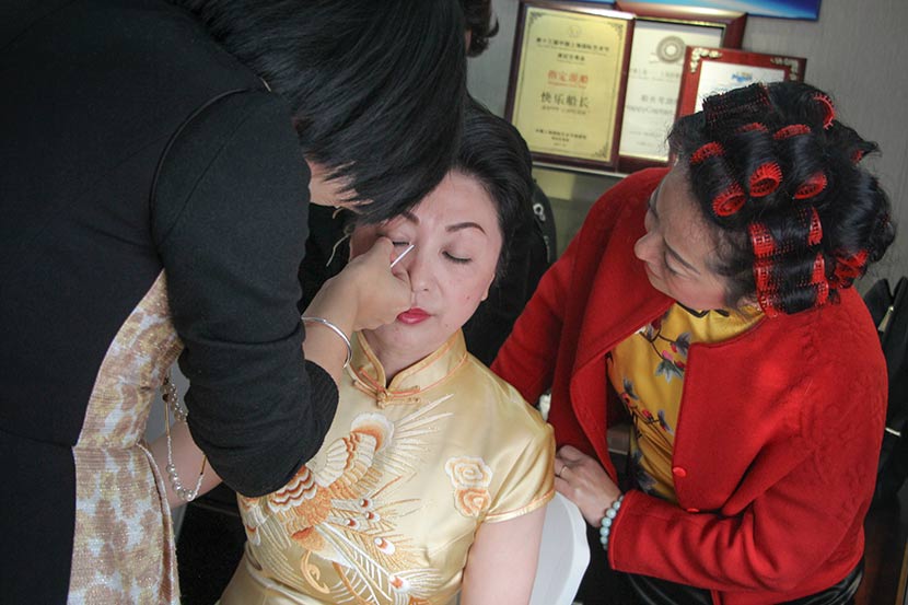 A makeup artist touches up Ni Hong’s 1920s Shanghai eyelash look before her performance in Shanghai, Dec. 10, 2017. Joyce Siu/Sixth Tone